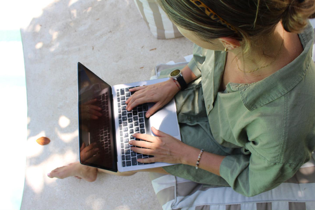 Mit dem Laptop am Strand sitzend 