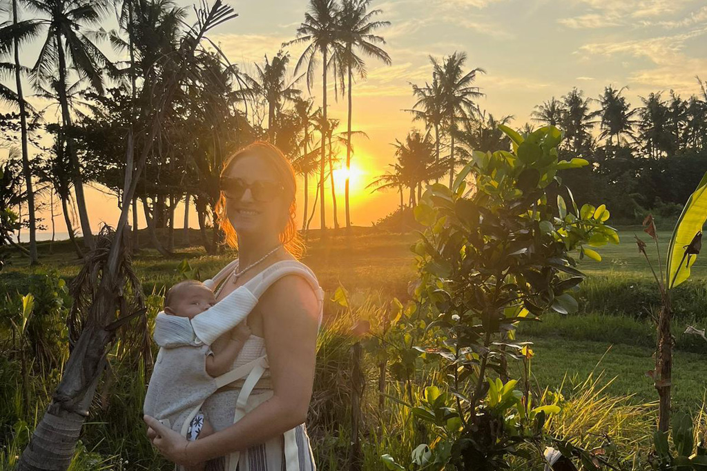 Geburt auf Bali: Mutter mit Baby im Sonnenuntergang umgeben von Palmen 
