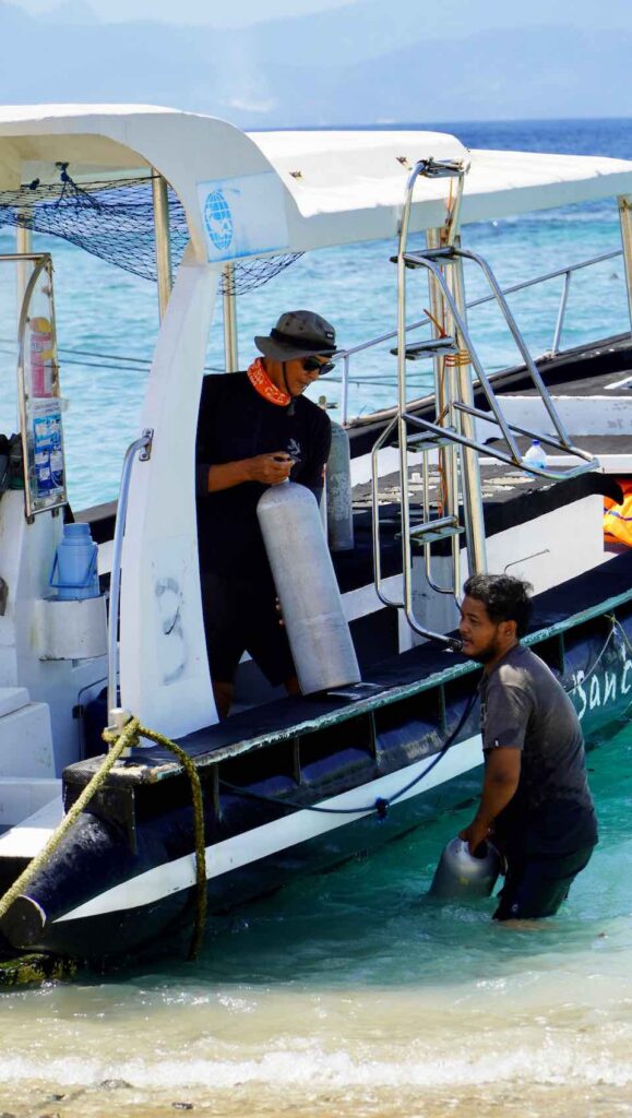 crew ladet sauerstoffflaschen fuer tauchgang auf das boot am strand