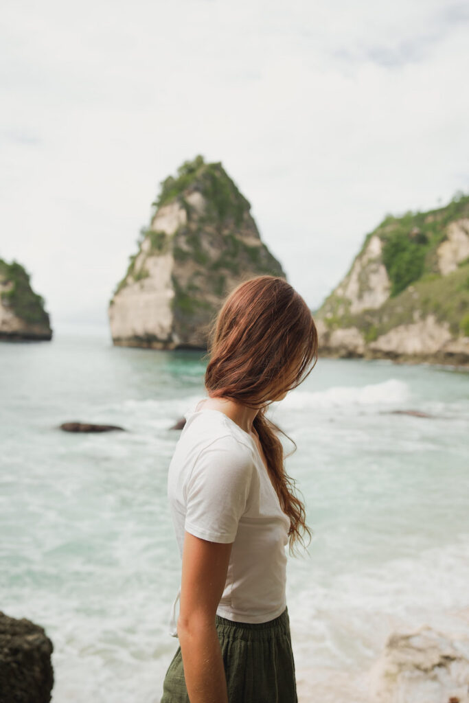junge frau blickt zum diamond beach und meer mit felsformation im hintergrund