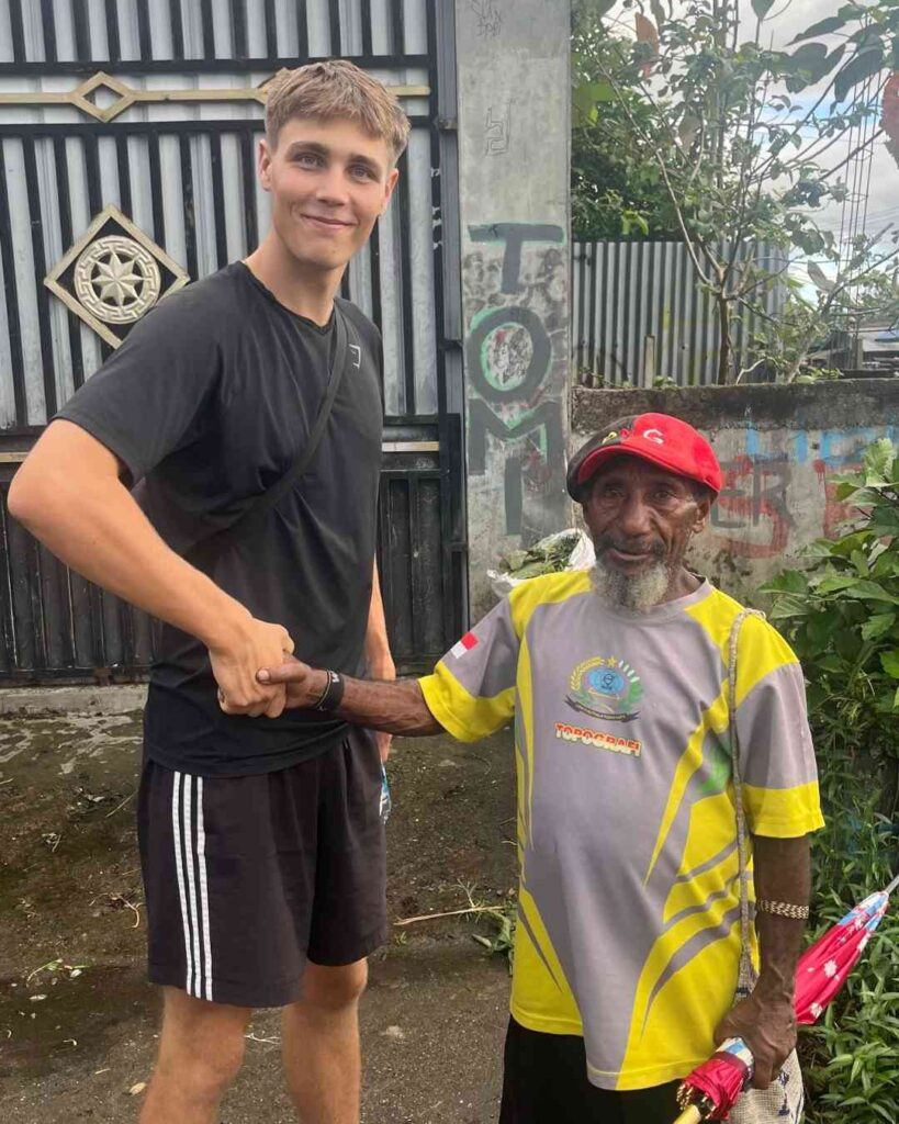 autor macht handschlag mit einheimischen mann in papua