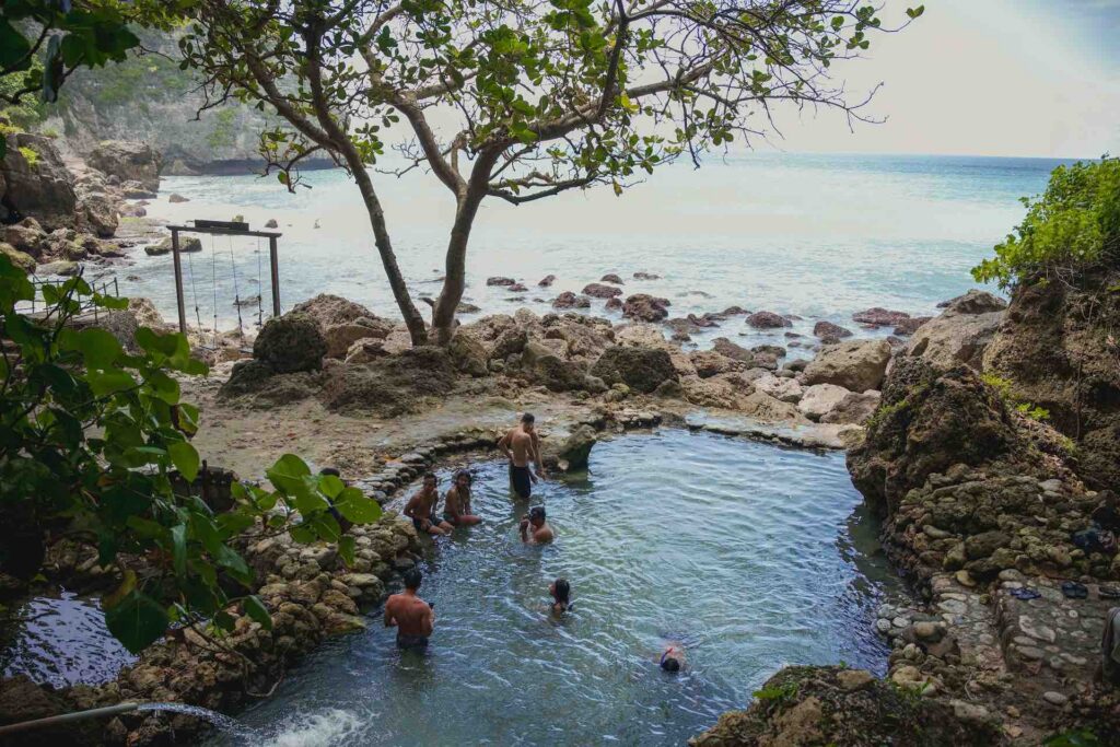 gruppe von locals badet in naturpools am tembeling beach in nusa penida