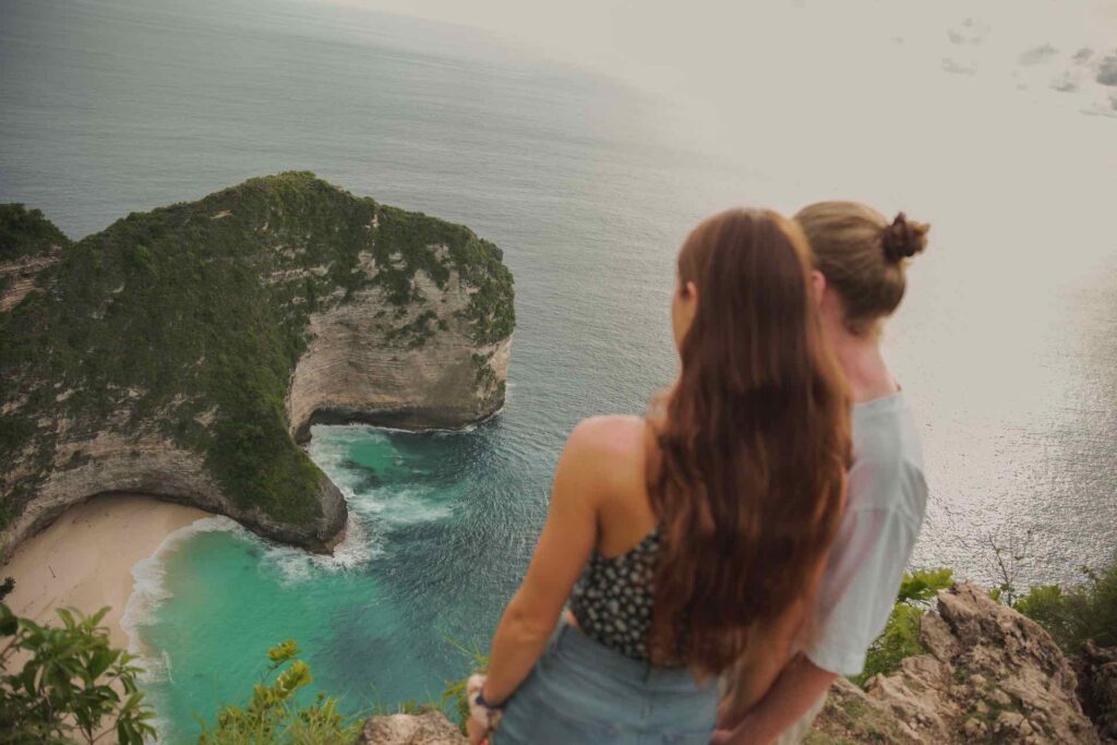 paar blickt von aussichtspunkt auf kelingking beach nusa penida 