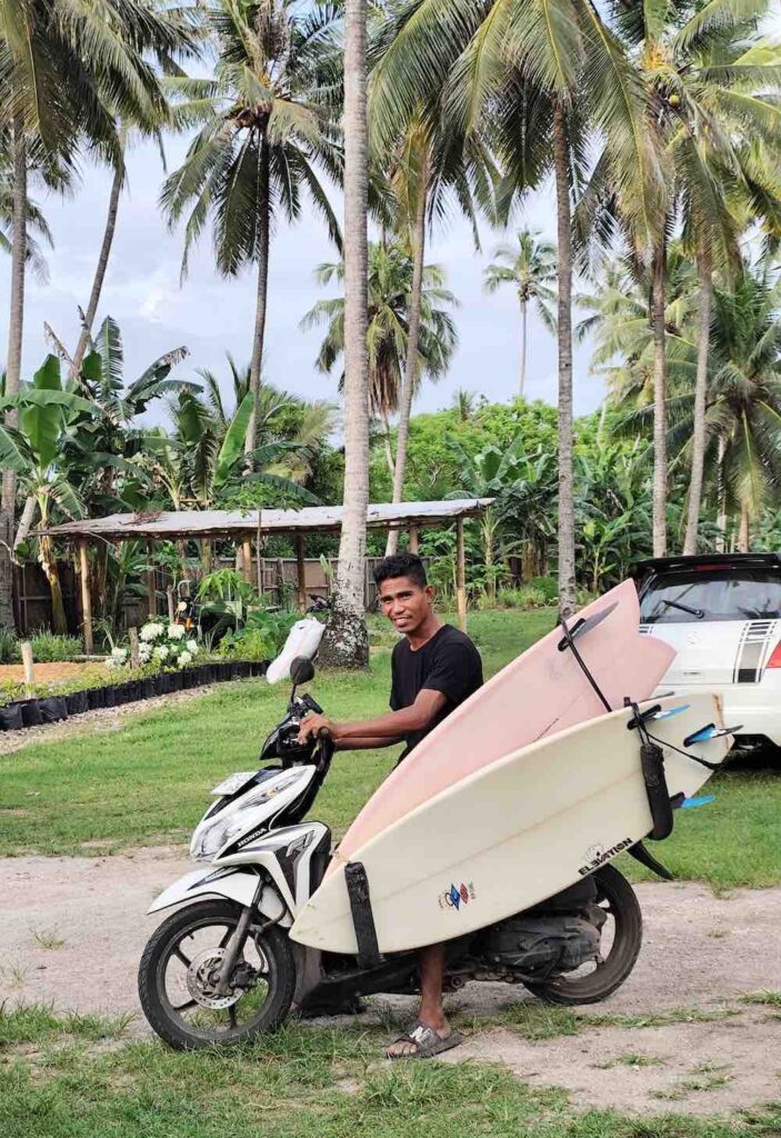 guide petrus mit surfboards auf dem roller in sumba