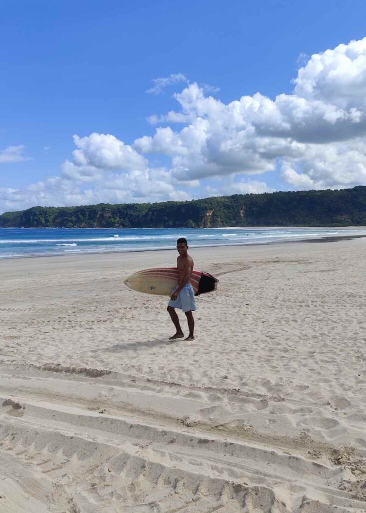 petrus am menschenleeren strand auf dem weg zum surfen in sumba